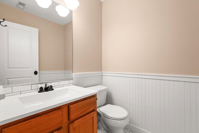 bathroom featuring a wainscoted wall, visible vents, vanity, and toilet