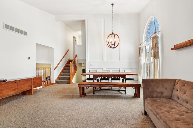 interior space with visible vents, stairway, a high ceiling, carpet flooring, and a chandelier