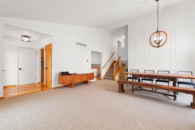 dining area featuring carpet floors, high vaulted ceiling, visible vents, stairway, and a chandelier