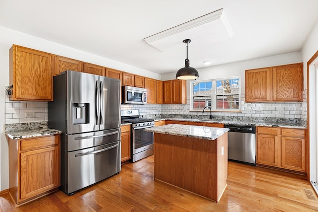 kitchen featuring light wood finished floors, light stone counters, stainless steel appliances, and a sink