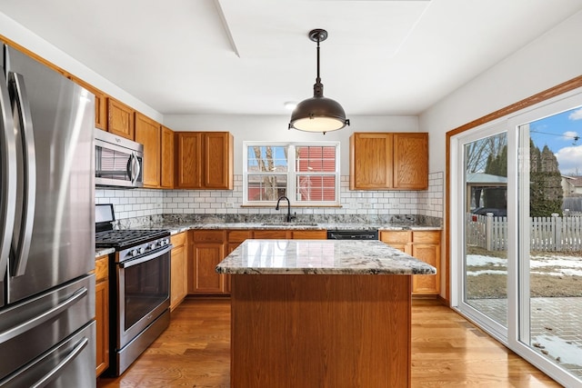 kitchen featuring light stone counters, light wood-style flooring, stainless steel appliances, a sink, and tasteful backsplash