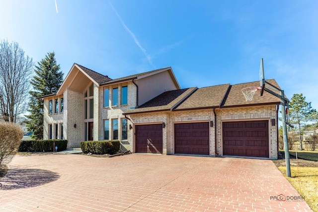 view of front of house featuring decorative driveway, brick siding, and a garage