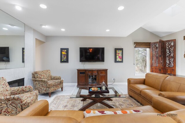 living room featuring lofted ceiling, recessed lighting, a fireplace, and baseboards