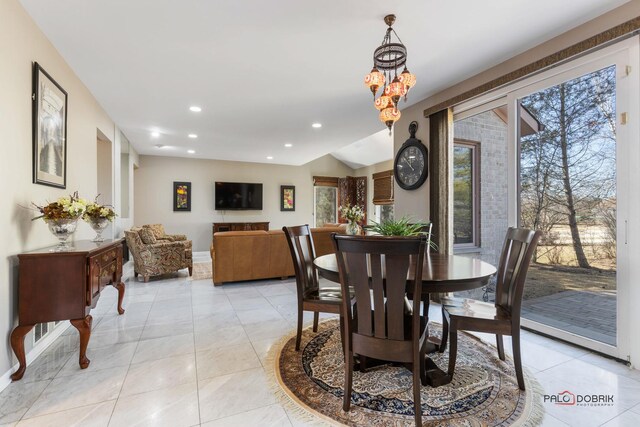 dining area with baseboards, lofted ceiling, light tile patterned floors, recessed lighting, and an inviting chandelier