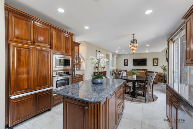 kitchen featuring decorative light fixtures, open floor plan, recessed lighting, stainless steel appliances, and dark stone counters