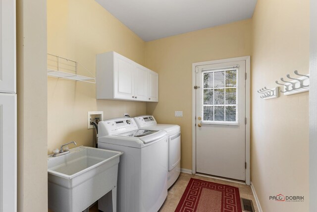 washroom with visible vents, baseboards, washing machine and dryer, cabinet space, and a sink