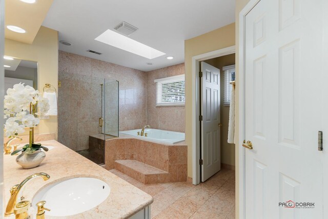 bathroom with a garden tub, a sink, a skylight, a shower stall, and double vanity