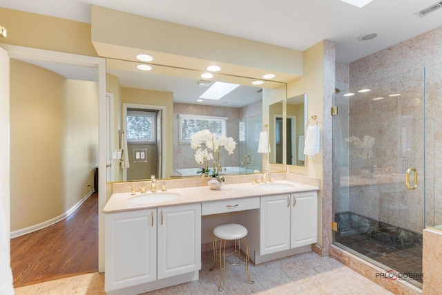 bathroom featuring a stall shower, a skylight, visible vents, and a sink