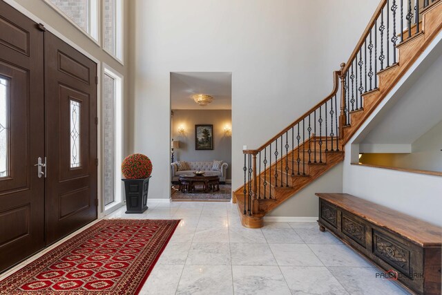 foyer entrance featuring baseboards, stairs, and a towering ceiling