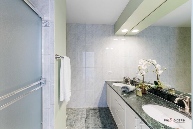 bathroom featuring tile walls, double vanity, and a sink