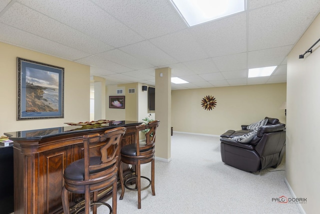 bar featuring a drop ceiling, light colored carpet, a dry bar, and baseboards