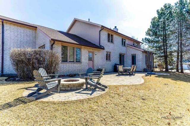 back of property featuring a yard, a patio, brick siding, and a chimney