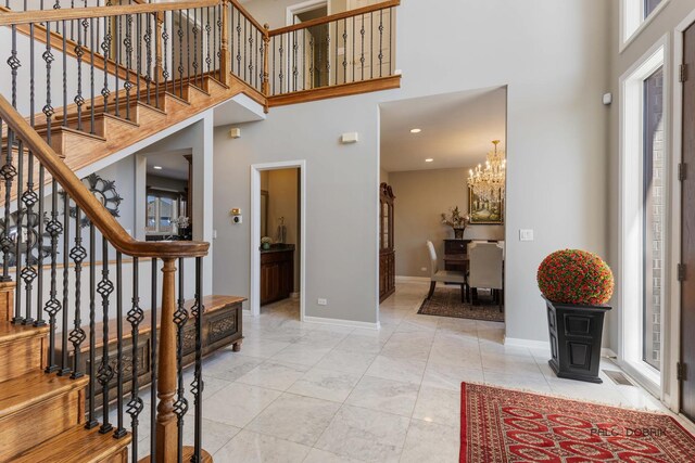 entrance foyer featuring a chandelier, stairway, a high ceiling, and baseboards