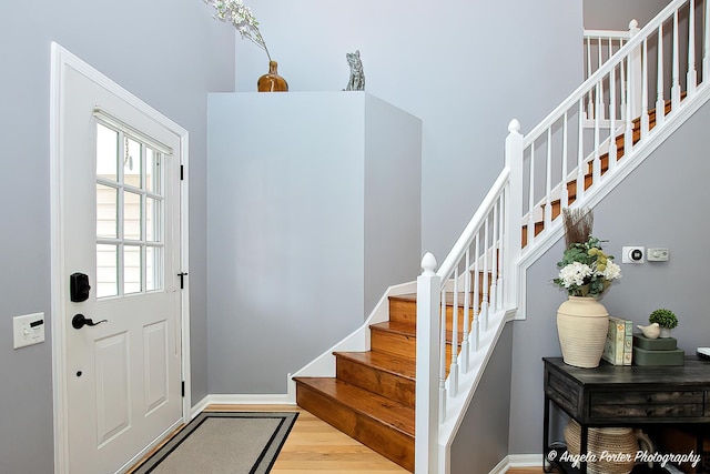 foyer entrance with stairway, light wood-style flooring, and baseboards