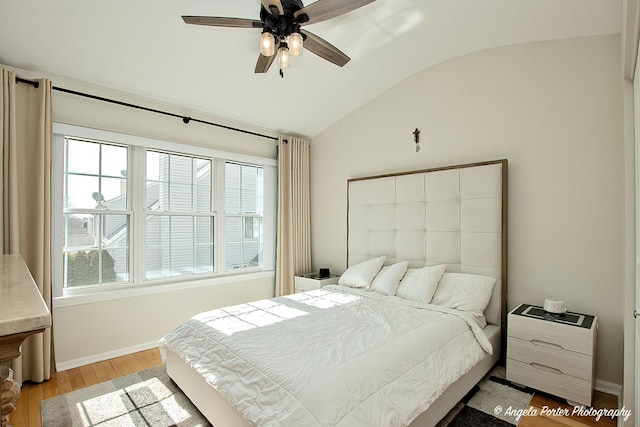 bedroom featuring vaulted ceiling, light wood finished floors, multiple windows, and baseboards