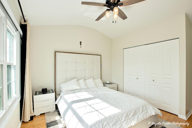 bedroom featuring vaulted ceiling, a closet, light wood-type flooring, and a ceiling fan