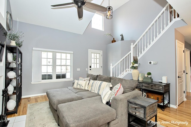 living room with stairs, a high ceiling, plenty of natural light, and light wood-style flooring