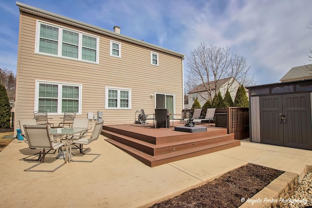 back of house with outdoor dining space, an outdoor structure, a wooden deck, and a storage unit