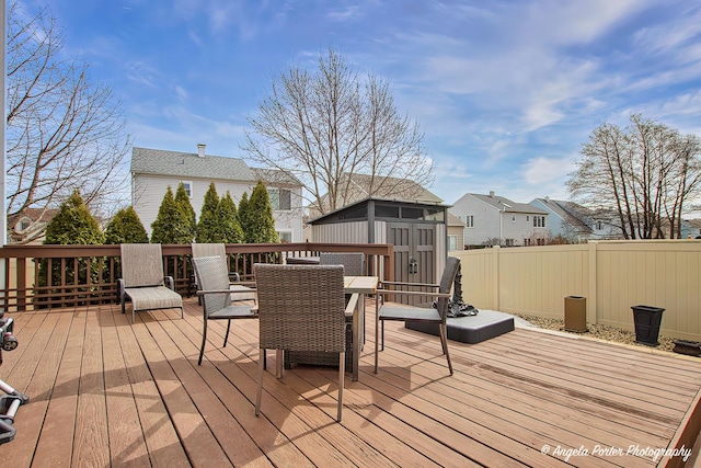 deck featuring a storage shed, an outbuilding, and fence