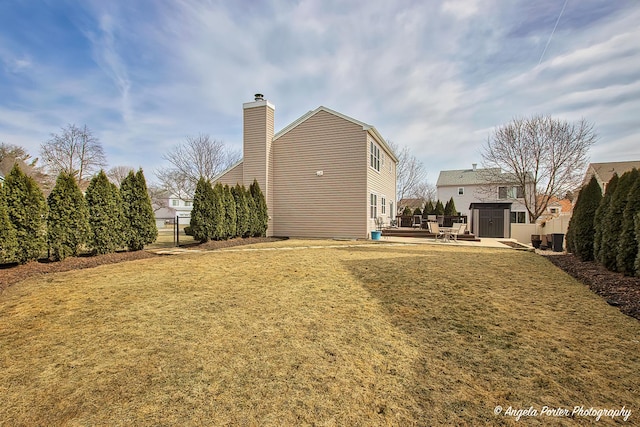 view of home's exterior featuring a storage shed, a lawn, a chimney, an outbuilding, and fence