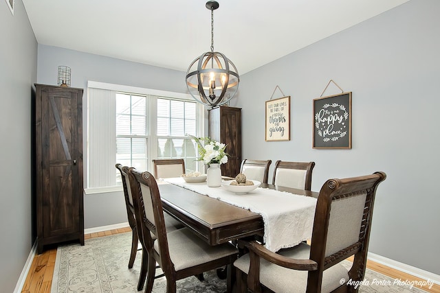 dining space featuring light wood-style floors, a notable chandelier, and baseboards