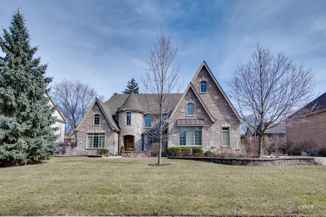 french country home with brick siding and a front yard