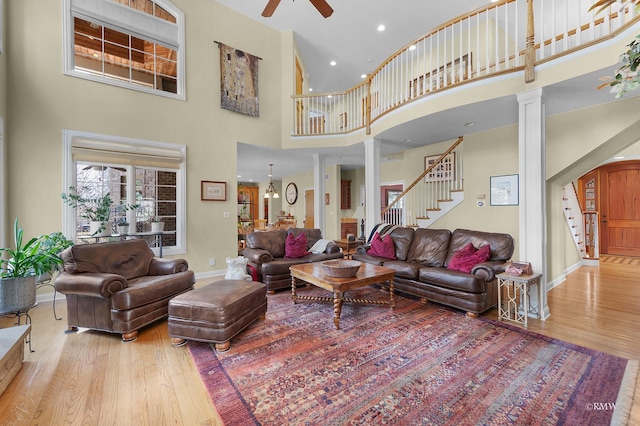 living area with stairs, decorative columns, wood finished floors, and baseboards