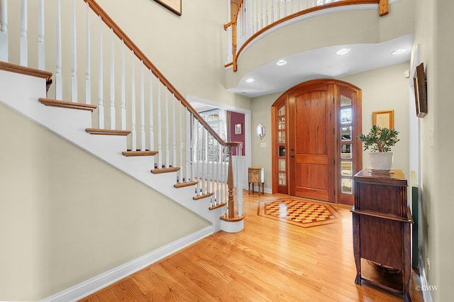 entrance foyer featuring wood finished floors, baseboards, a high ceiling, recessed lighting, and arched walkways