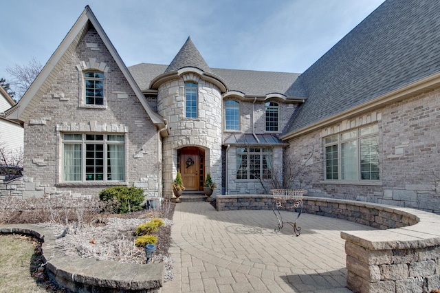 view of front of house featuring brick siding and roof with shingles