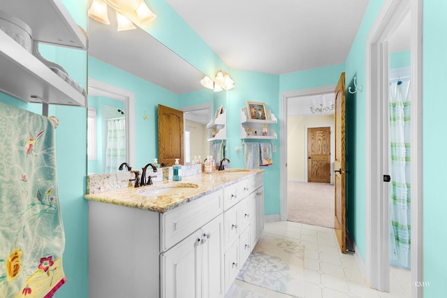 full bath featuring double vanity, baseboards, and a sink