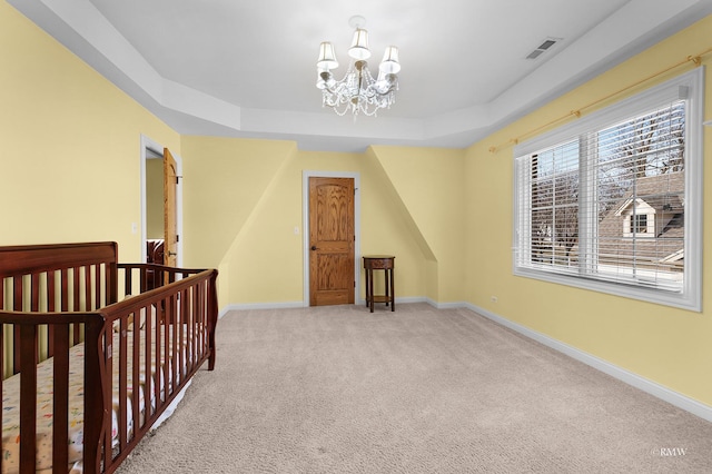 carpeted bedroom with a tray ceiling, baseboards, visible vents, and a chandelier