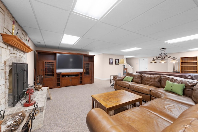 living room featuring a fireplace, stairs, carpet, and a drop ceiling