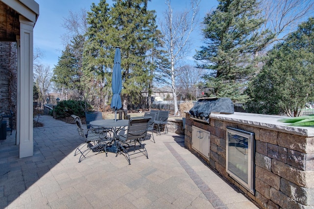 view of patio with outdoor dining space, fence, exterior kitchen, wine cooler, and a grill