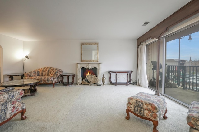 sitting room with a fireplace with flush hearth, visible vents, and carpet flooring