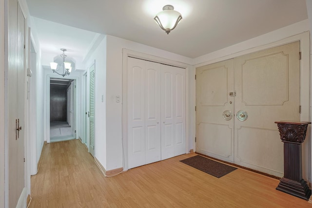 entrance foyer with light wood-style flooring, a chandelier, and baseboards