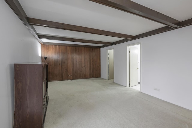 spare room with light carpet, beamed ceiling, and wooden walls