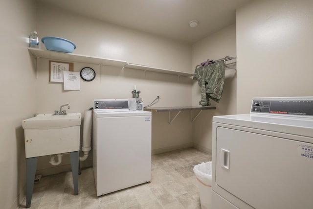 laundry room featuring washing machine and clothes dryer, a sink, and baseboards