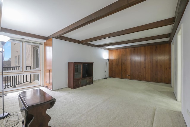 living area with wood walls, beamed ceiling, and light colored carpet