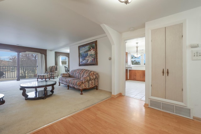 living room with arched walkways, wood finished floors, visible vents, and baseboards