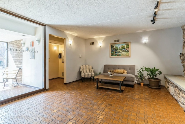 living room featuring visible vents, a textured ceiling, and a healthy amount of sunlight