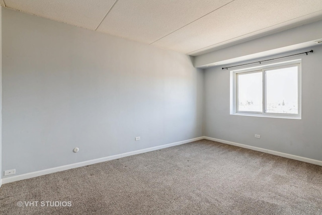 carpeted spare room featuring baseboards and a textured ceiling