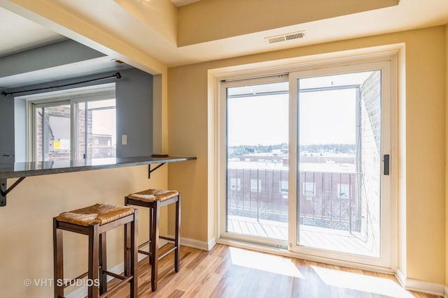 doorway featuring light wood-style floors, visible vents, and baseboards