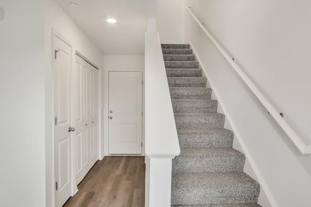 stairs with wood finished floors and recessed lighting