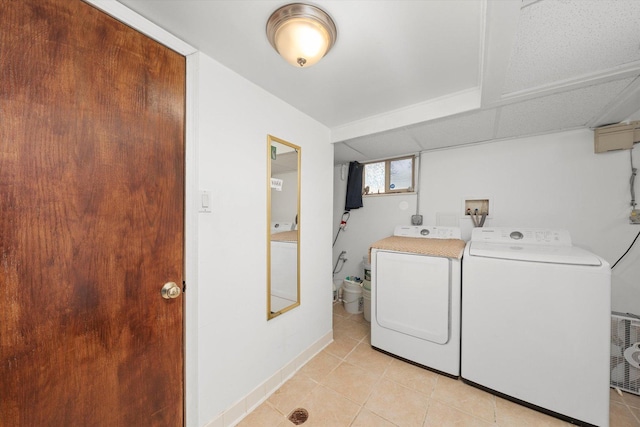 clothes washing area featuring laundry area, baseboards, washing machine and clothes dryer, and light tile patterned flooring