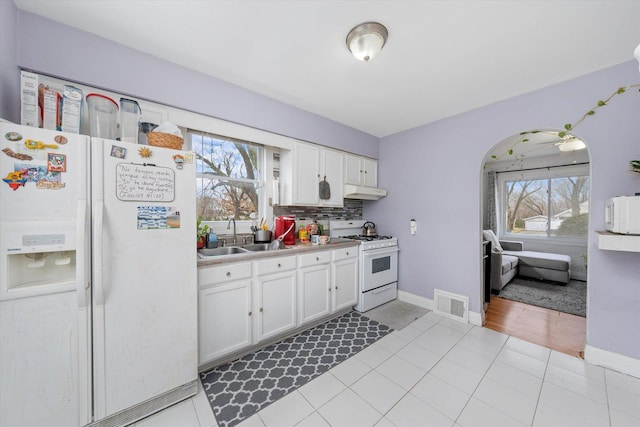 kitchen featuring white appliances, plenty of natural light, a sink, and visible vents