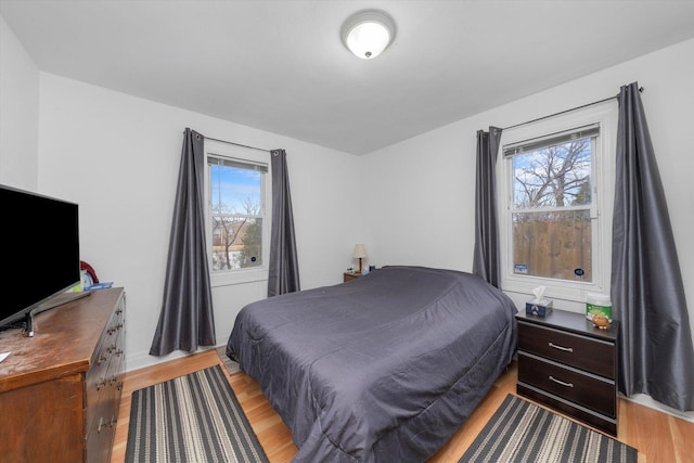 bedroom with light wood finished floors and multiple windows