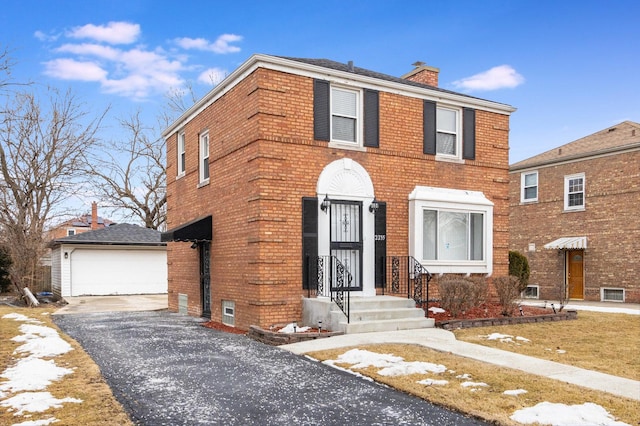 colonial house featuring a garage, a chimney, an outbuilding, and brick siding