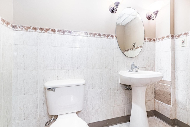 bathroom featuring toilet, tile walls, and wainscoting