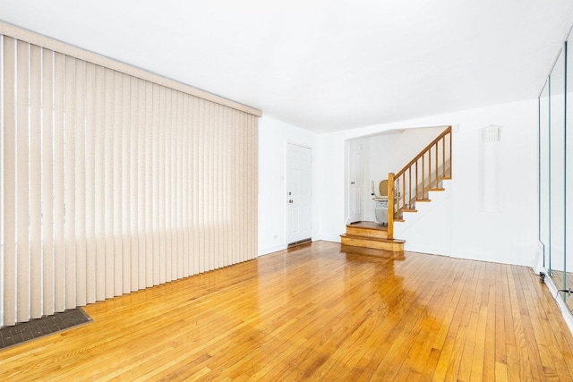 empty room featuring stairs and light wood-type flooring