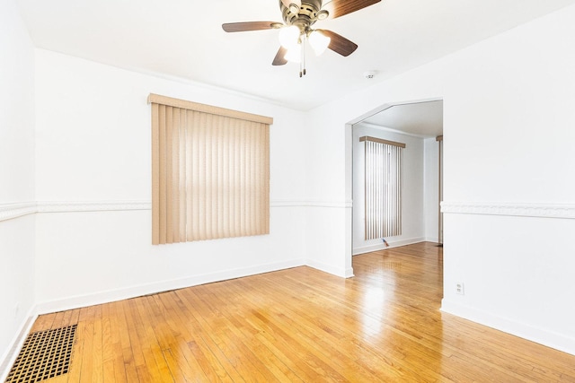 spare room with a ceiling fan, visible vents, baseboards, and hardwood / wood-style flooring